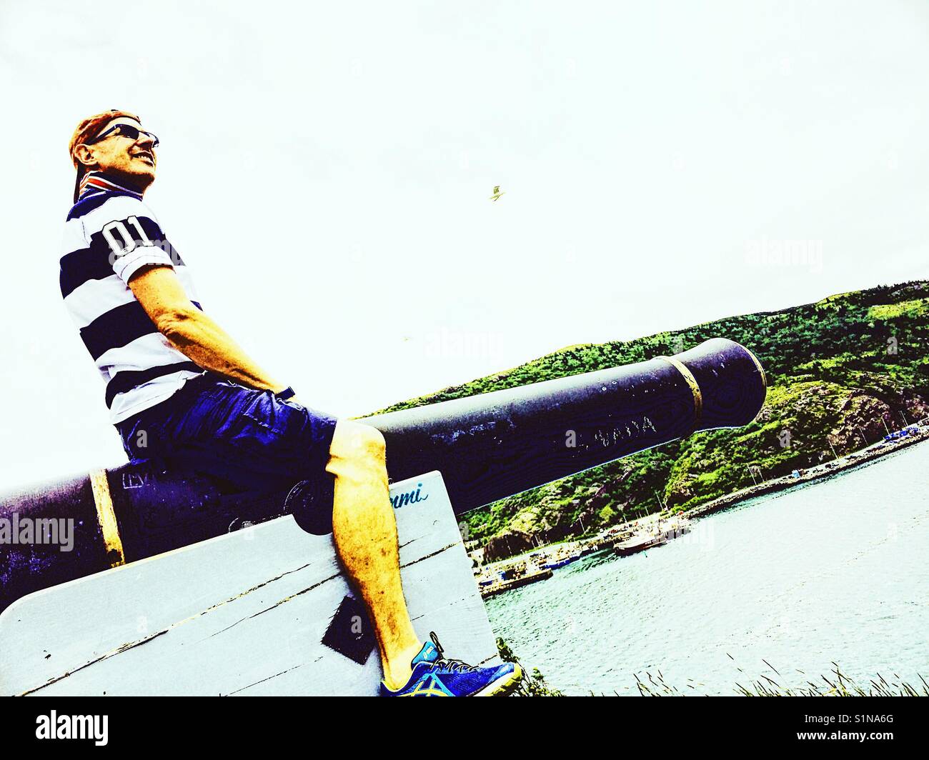 Middle aged Scandinavian man posing on cannon - Smartphone Captured Stock Image