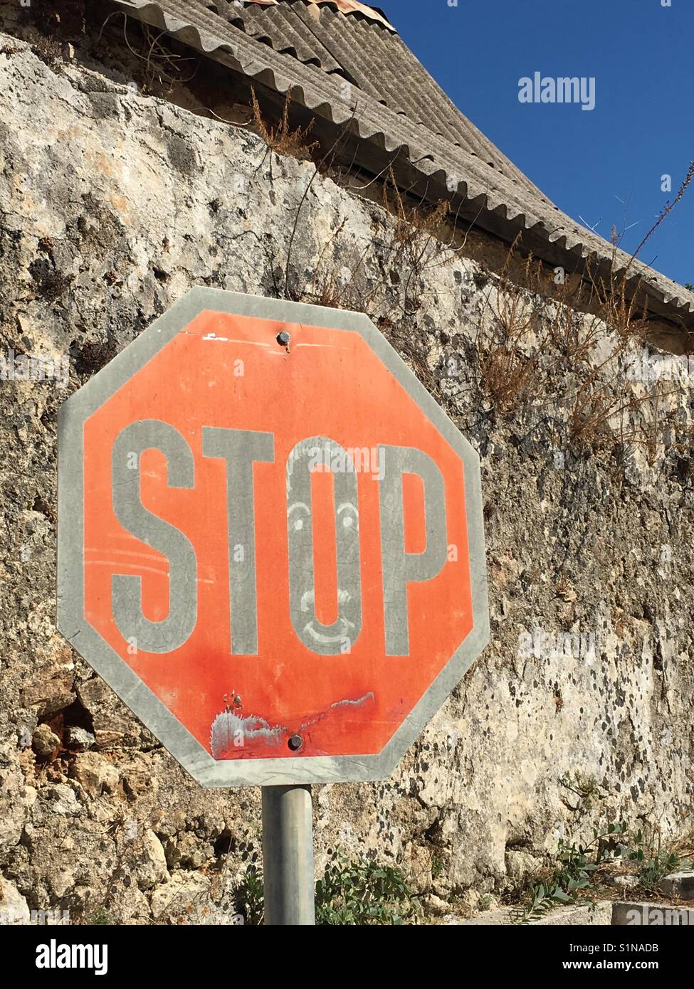 Stop sign against an old house on Kefalonia in Greece - Smartphone Captured Stock Image