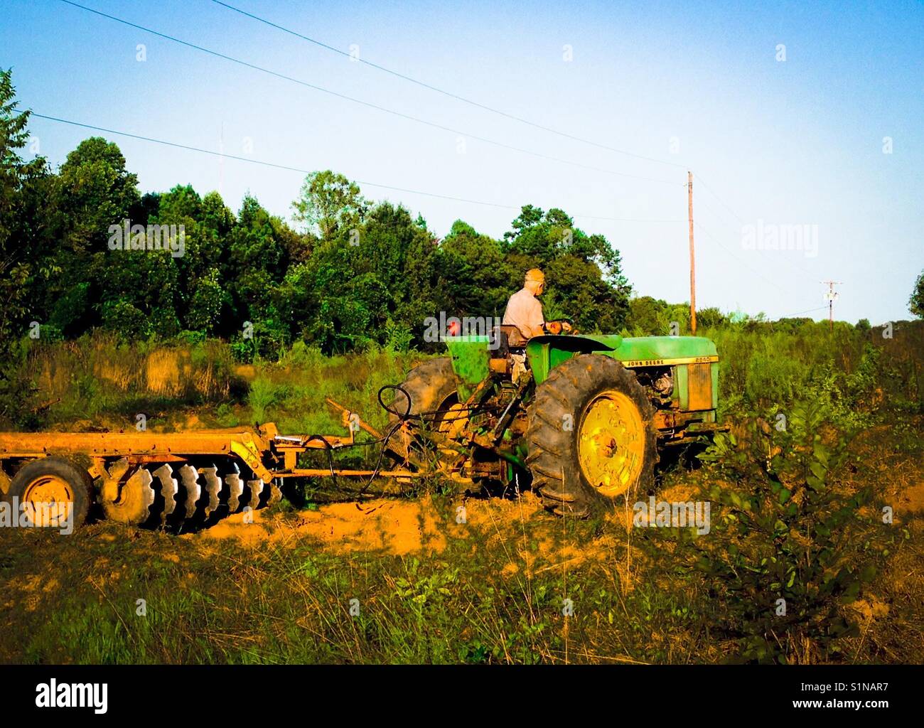 Man on John Deere tractor discs field in North Carolina Stock Photo Alamy