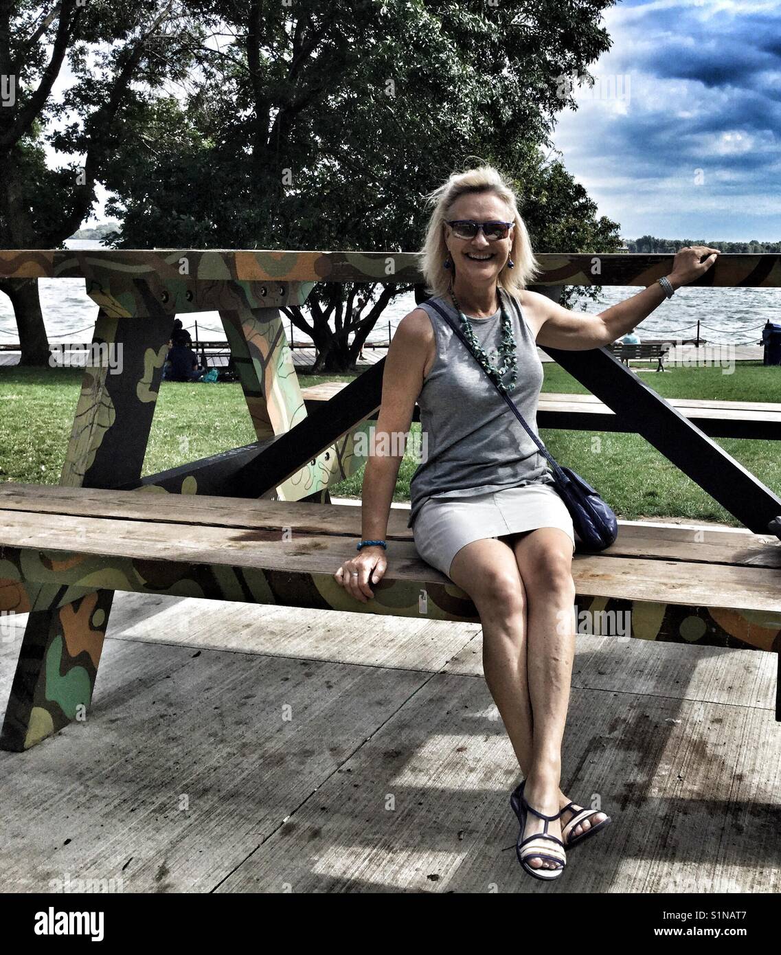 Woman sitting on an oversized picnic table in a park along Toronto's waterfront. - Smartphone Captured Stock Image