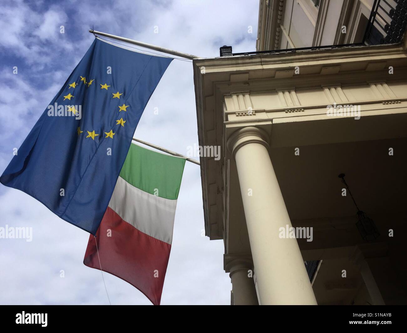 An EU flag flies next to the Italian flag outside a government building in London Stock Photo