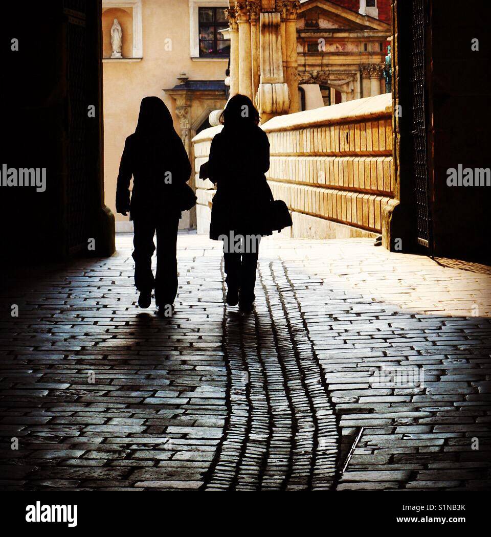 Two women walking in a paved street in Cracow, Poland - Smartphone Captured Stock Image