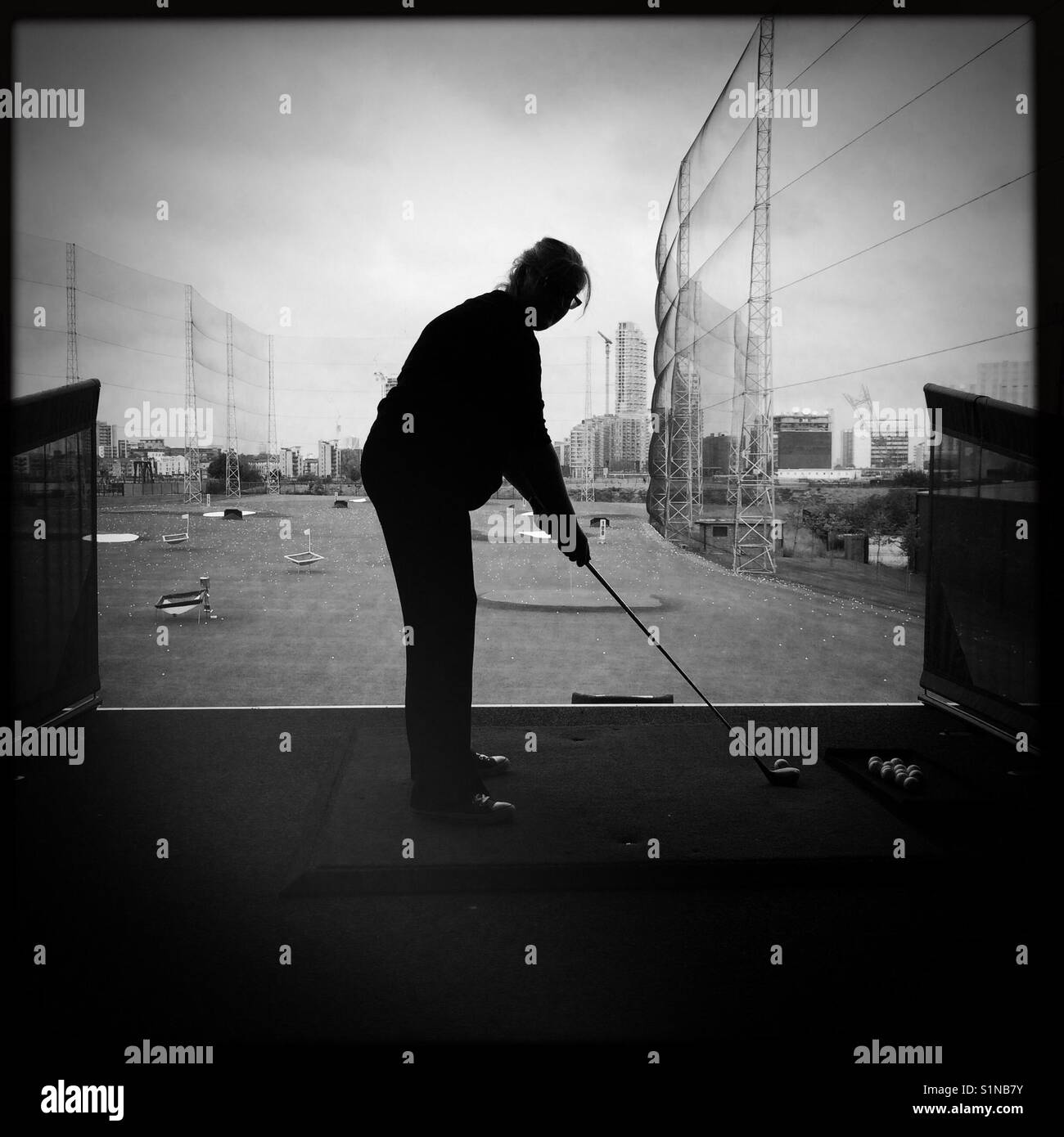 Woman about to swing at the ball at a driving range - Smartphone Captured Stock Image