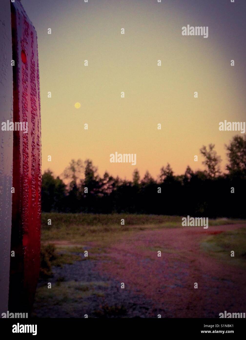 Morning moon- full moon on morning light framed by field and pickup - Smartphone Captured Stock Image