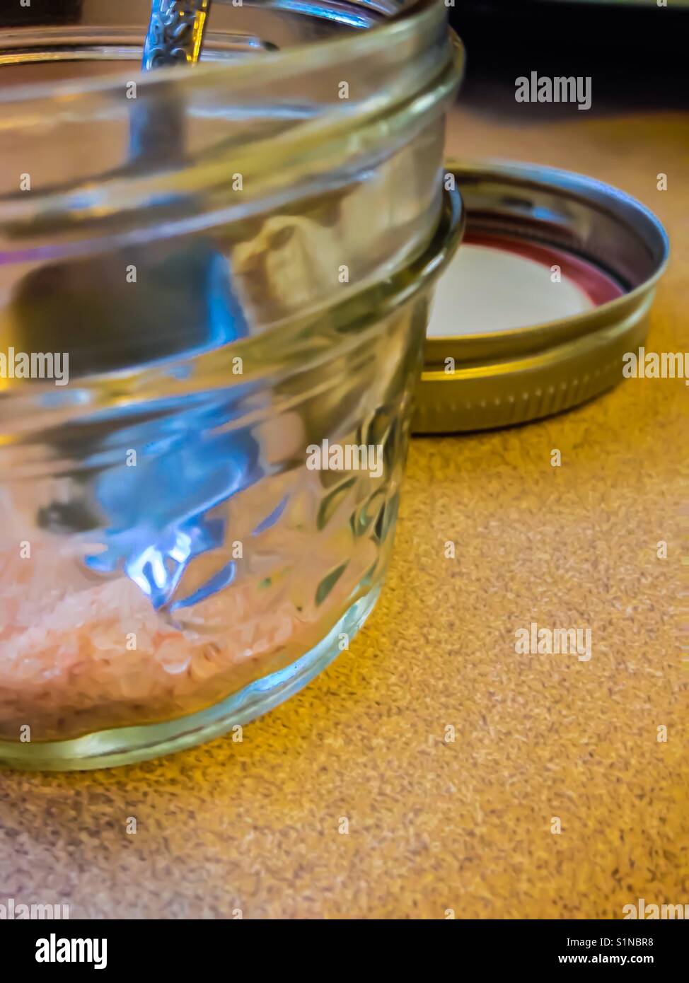 Spoon dips inside small canning jar for Himalayan salt- with lid - Smartphone Captured Stock Image