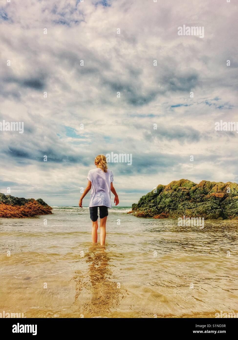 Young girl paddling in the sea at Newborough beach on Anglesey Stock Photo