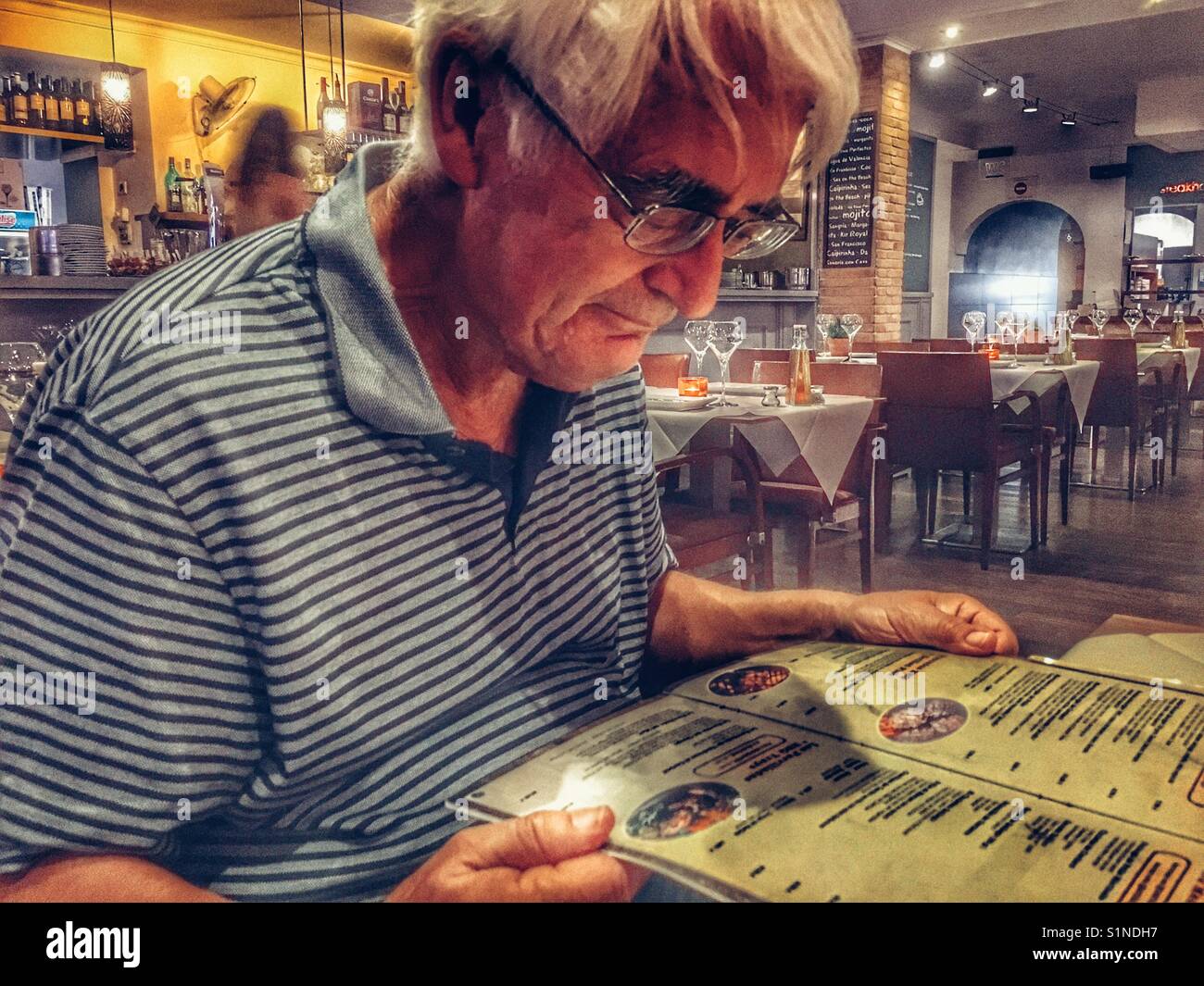Man in a restaurant, reading the menu - Smartphone Captured Stock Image