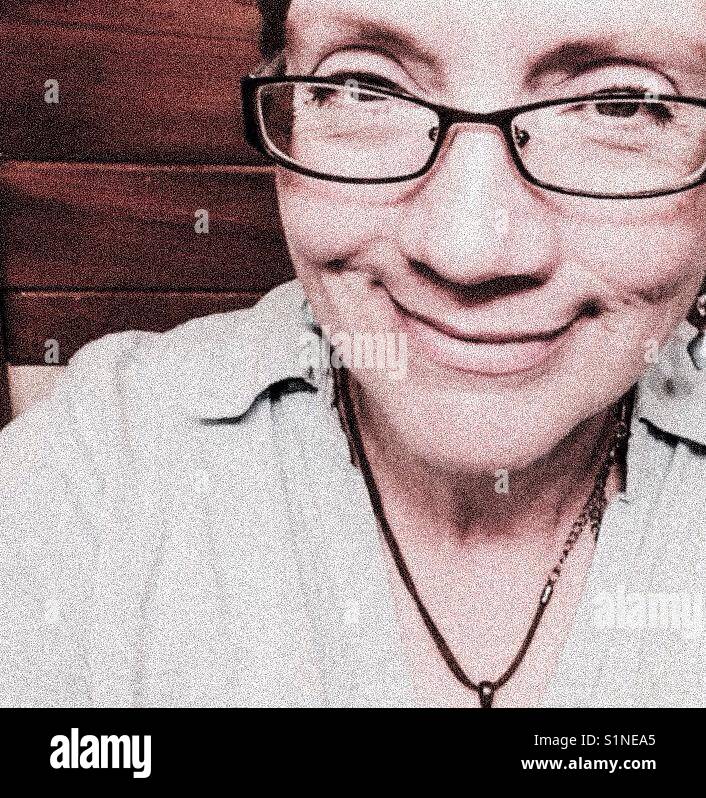 Happy mature woman with glasses, necklace, and short hair - Smartphone Captured Stock Image