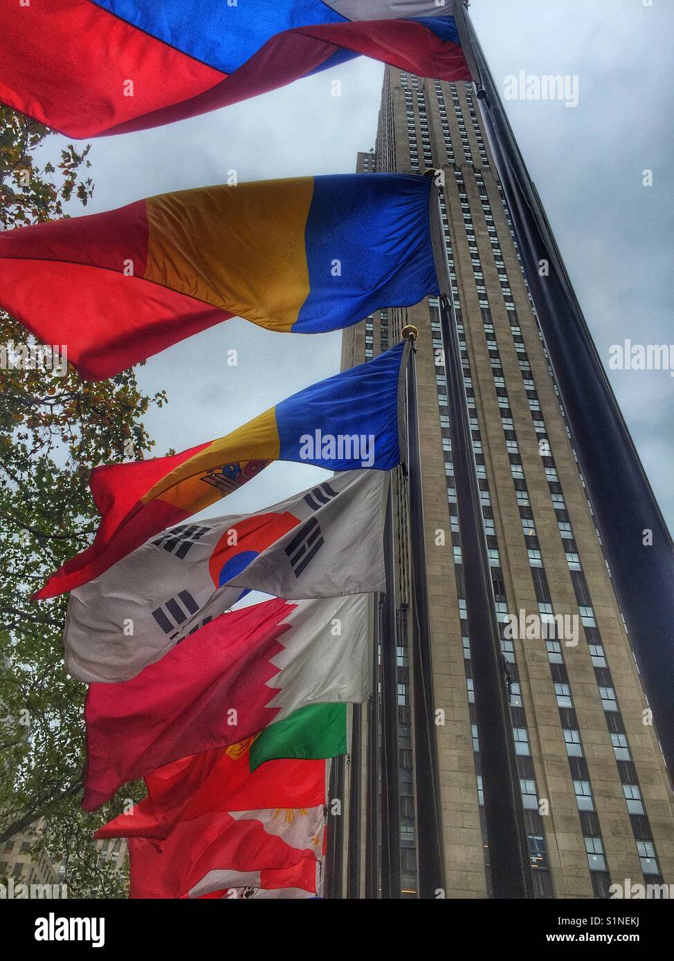 The flags of world countries fly at the Rockefeller Center with the Rockefeller building in the background, New York City, New York. Stock Photo