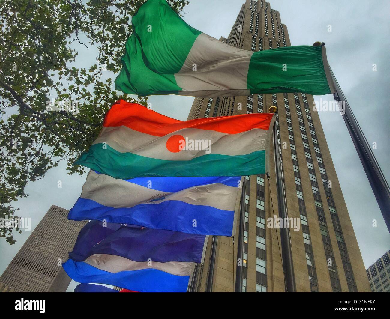 Flags of world nations fly at the Rockefeller Center with the Rockefeller building in the background, New York City, New York Stock Photo