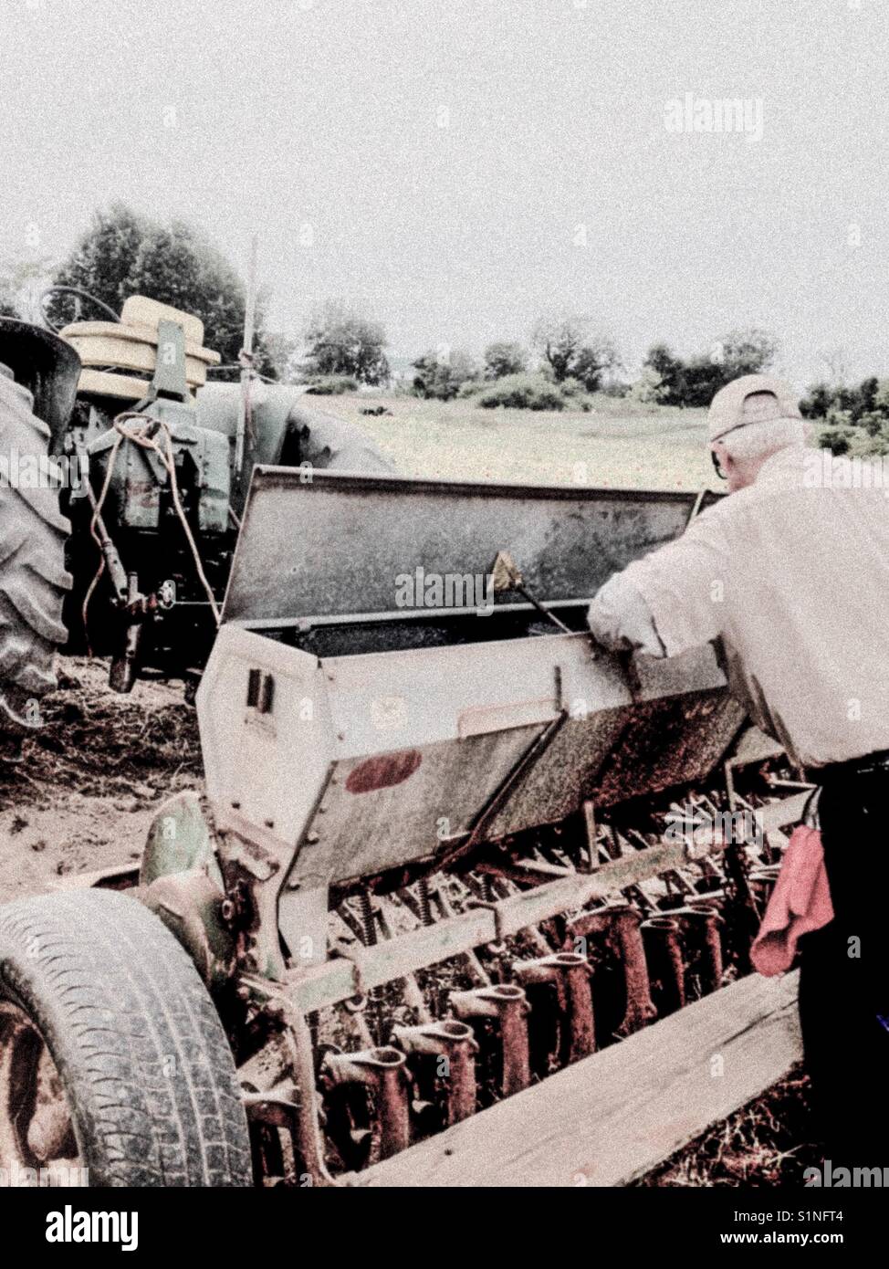 Farmer adjusts drill setting to plant clover in North Carolina field - Smartphone Captured Stock Image