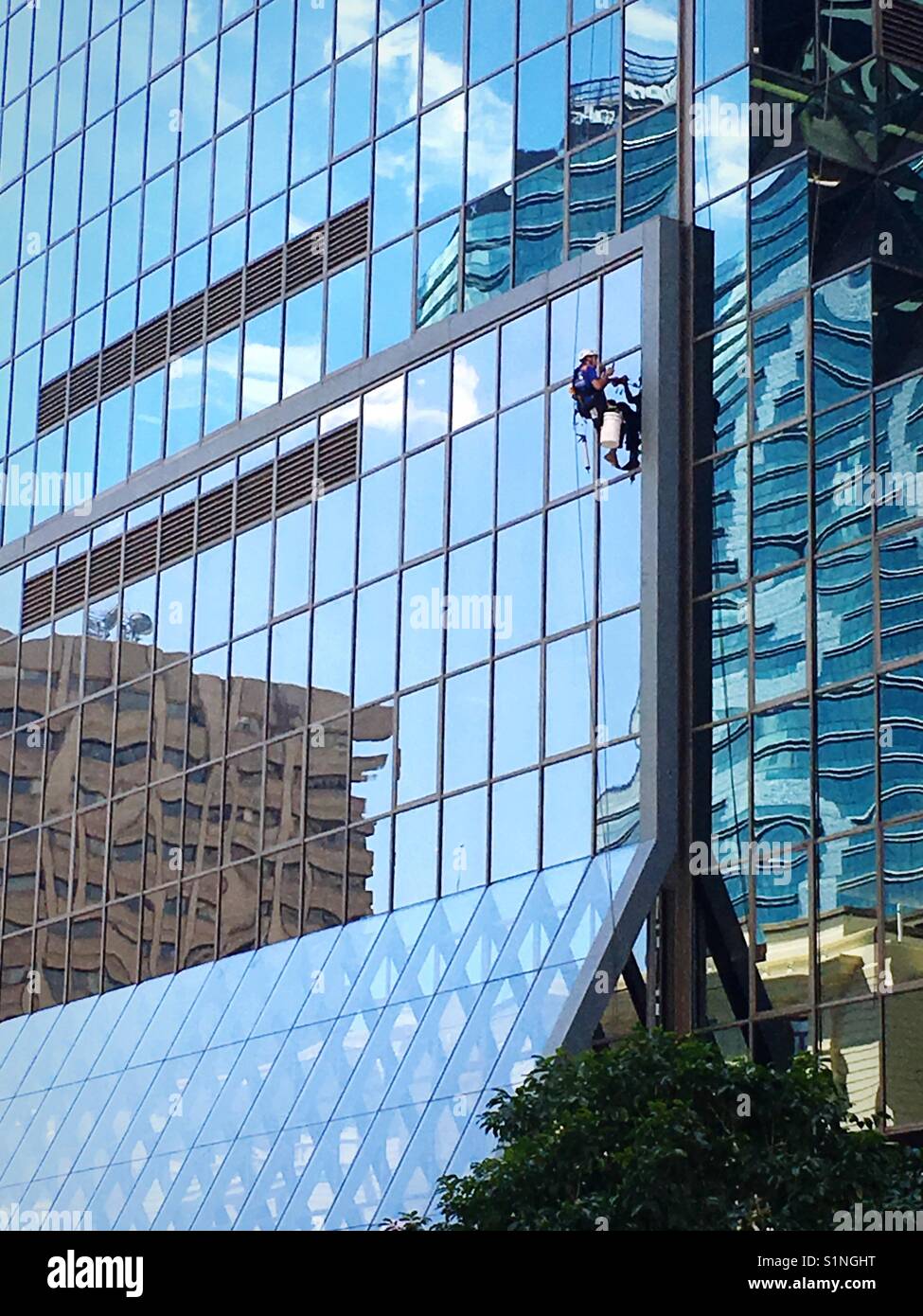 Window cleaner hanging on the side of a building Stock Photo