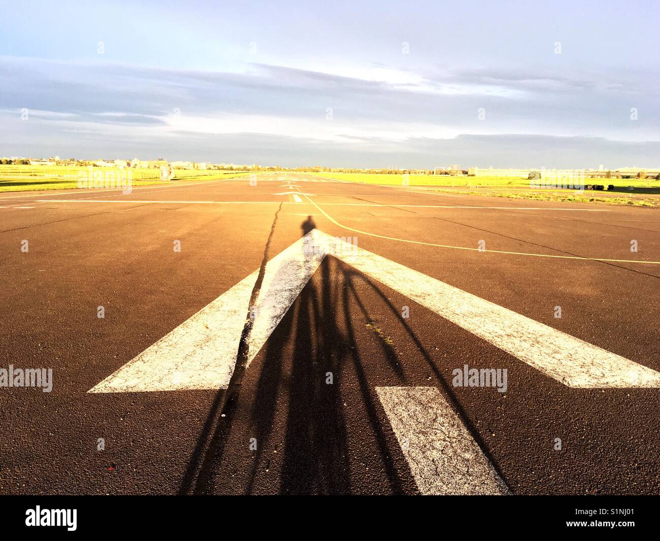 Long Shadow of a man on a bike on Tempelhofer Feld at sunrise, Berlin, Germany - Smartphone Captured Stock Image