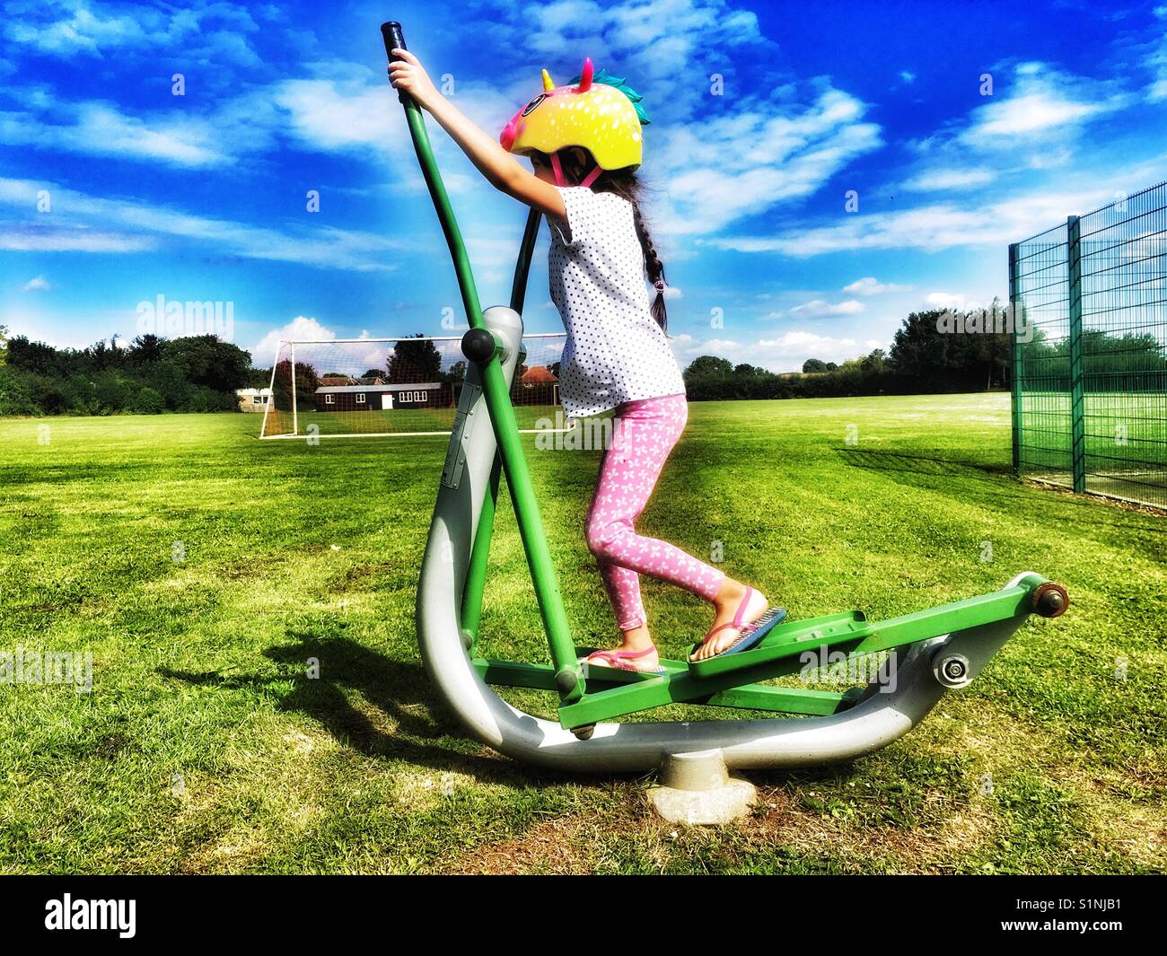Girl using public exercise machine - Smartphone Captured Stock Image
