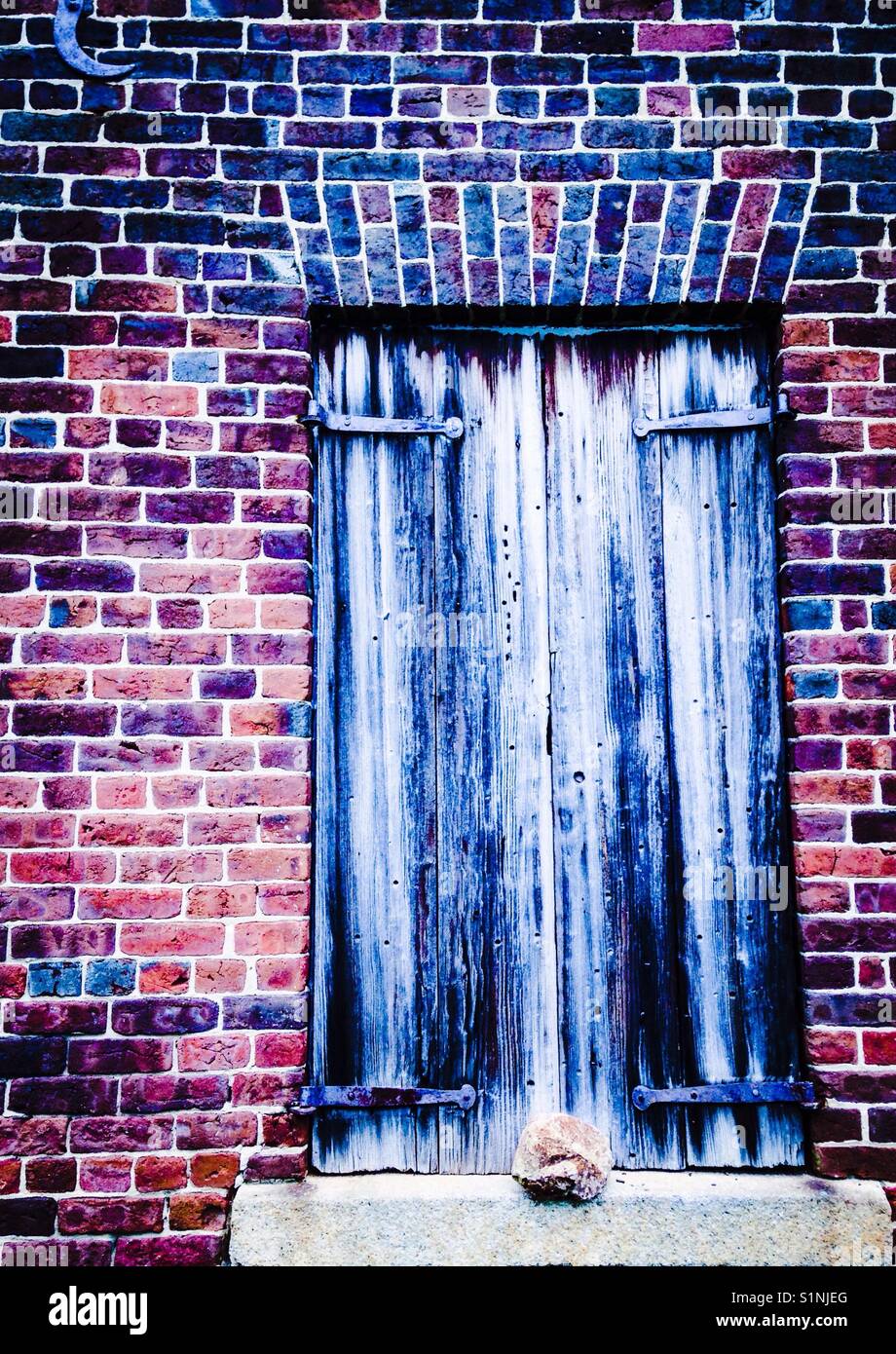 Wooden shutters in old brick building with wrought iron hinges - Smartphone Captured Stock Image