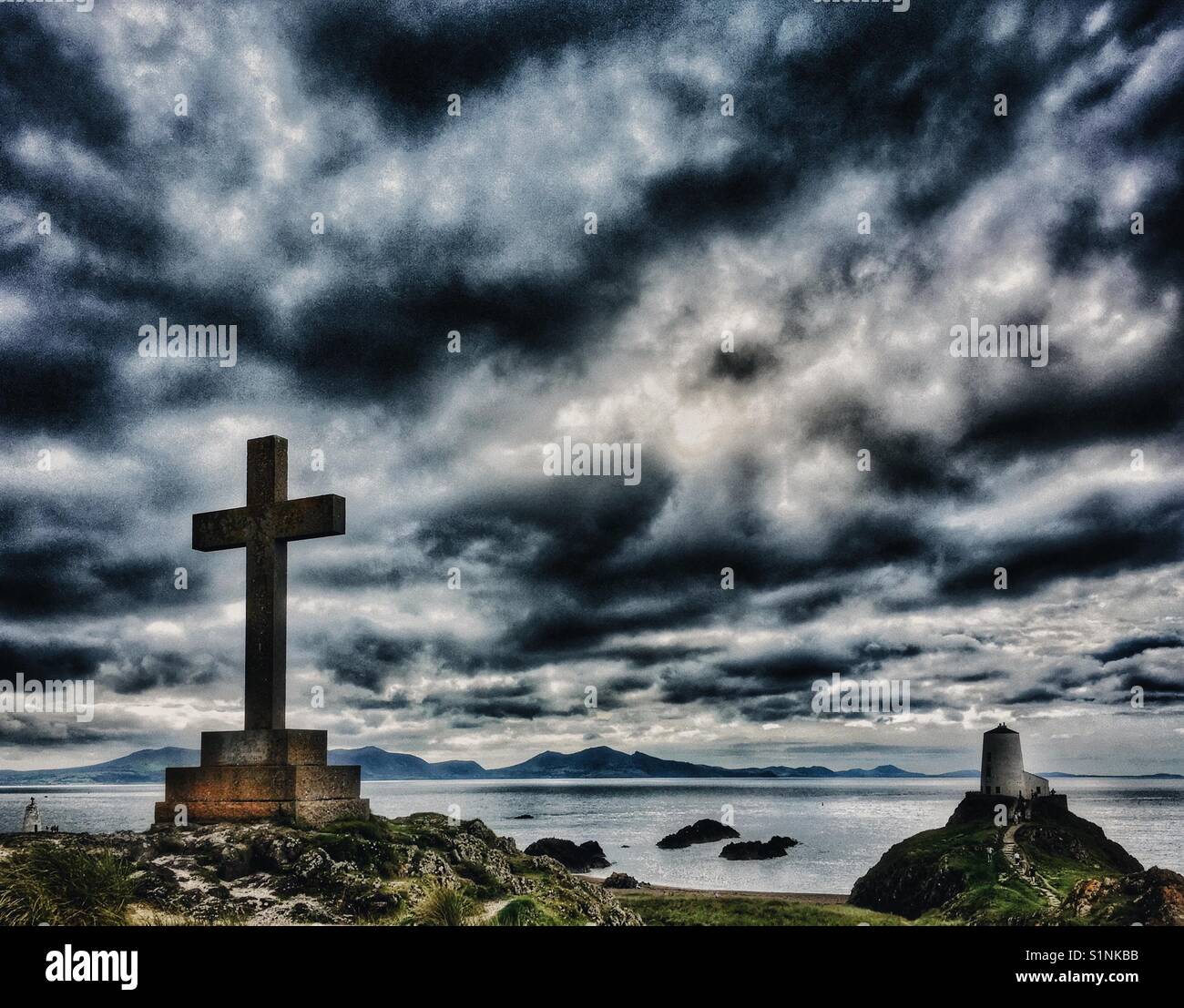 Cross memorial and lighthouse on Llanddwyn island off Newborough beach on Anglesey, North Wales - Smartphone Captured Stock Image