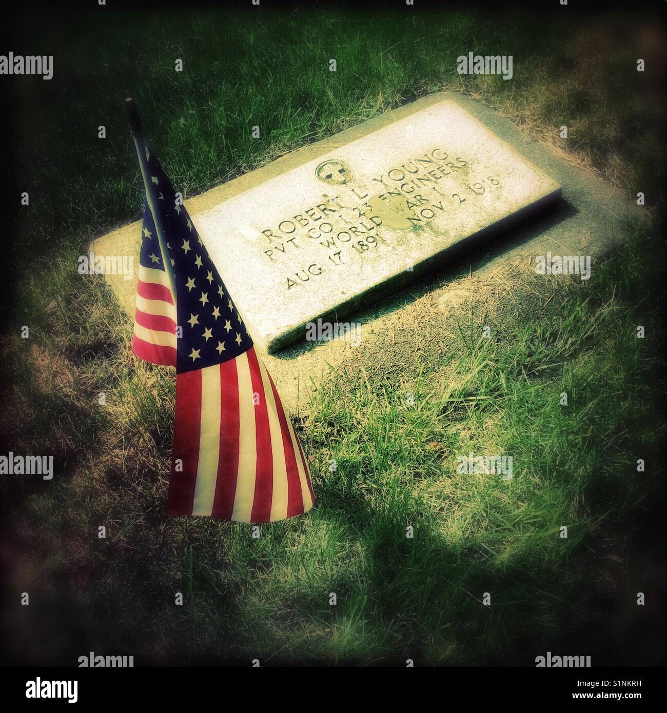 Vintage soldier veteran gravestone in cemetery decorated with American flag for Memorial Day remembrance, Bozeman, Montana, USA. - Smartphone Captured Stock Image