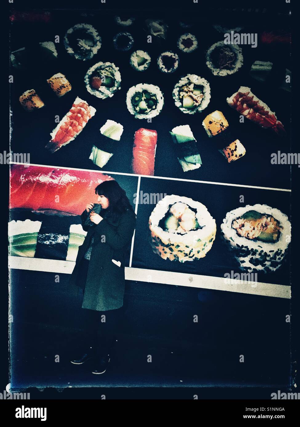 A female having snack in front of a large billboard of Japanese sushi, London, UK Stock Photo