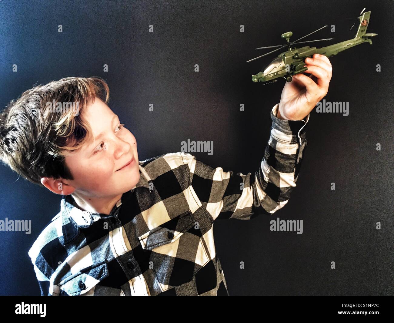 Boy playing with model Apache attack helicopter - Smartphone Captured Stock Image