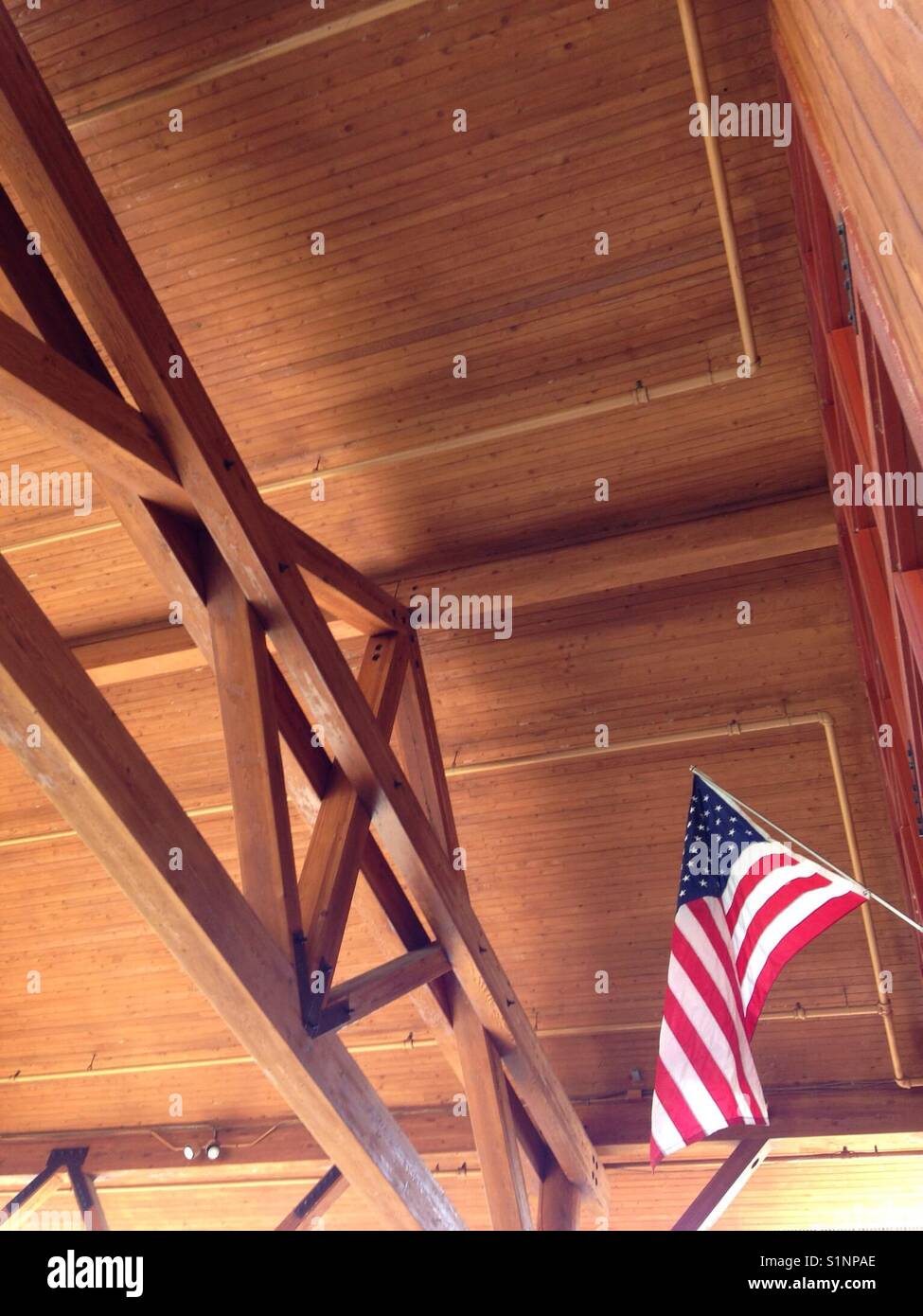 Wooden beams on a ceiling with an American flag displayed. Stock Photo