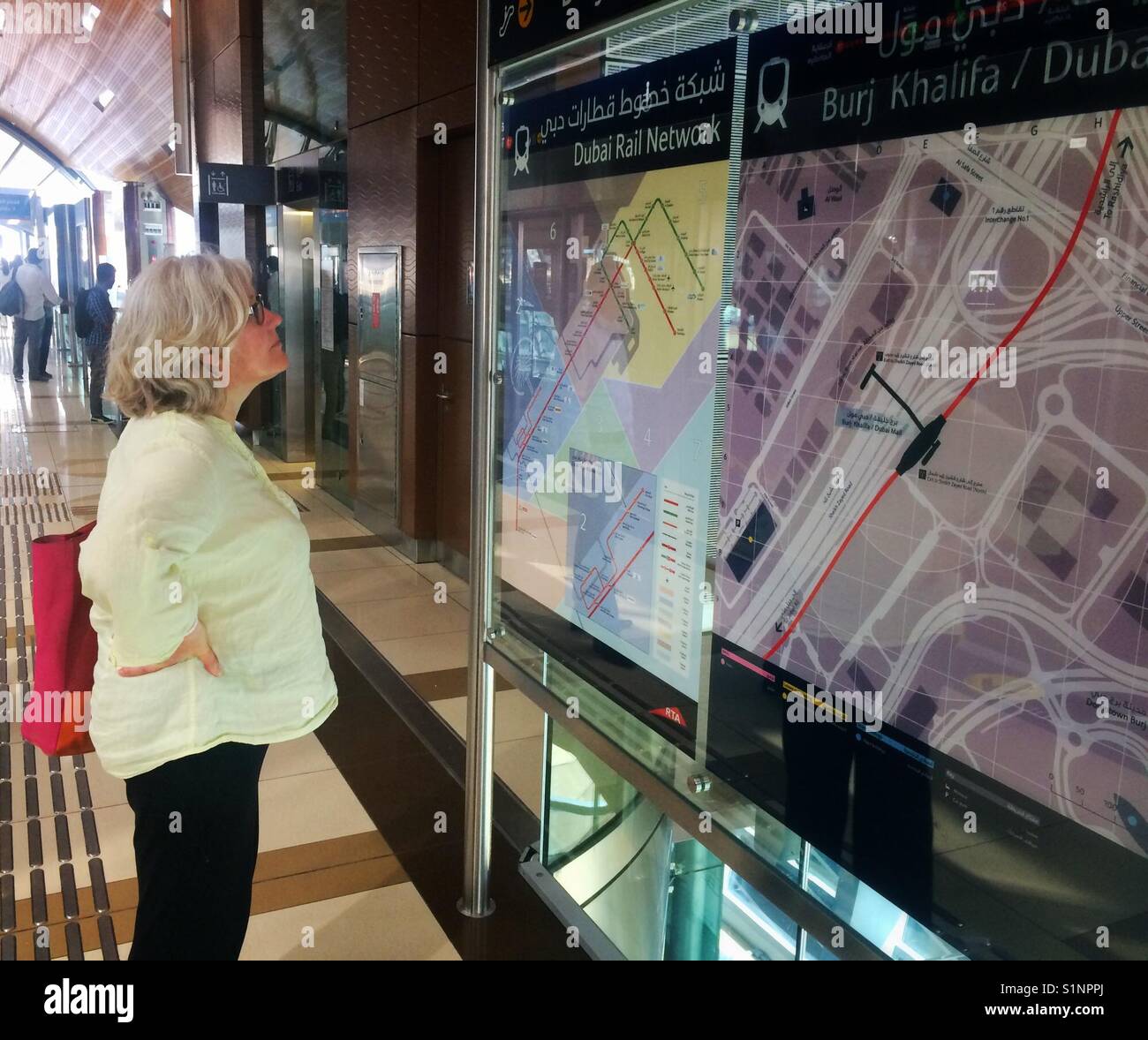 Woman looking at Dubai transport map - Smartphone Captured Stock Image