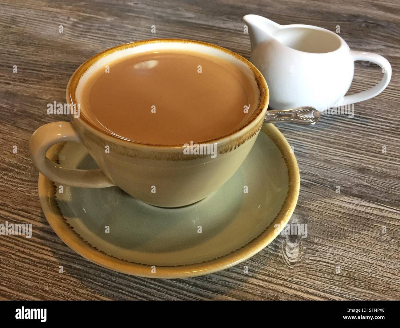 Americano coffee with milk and milk jug on a wooden table Stock Photo