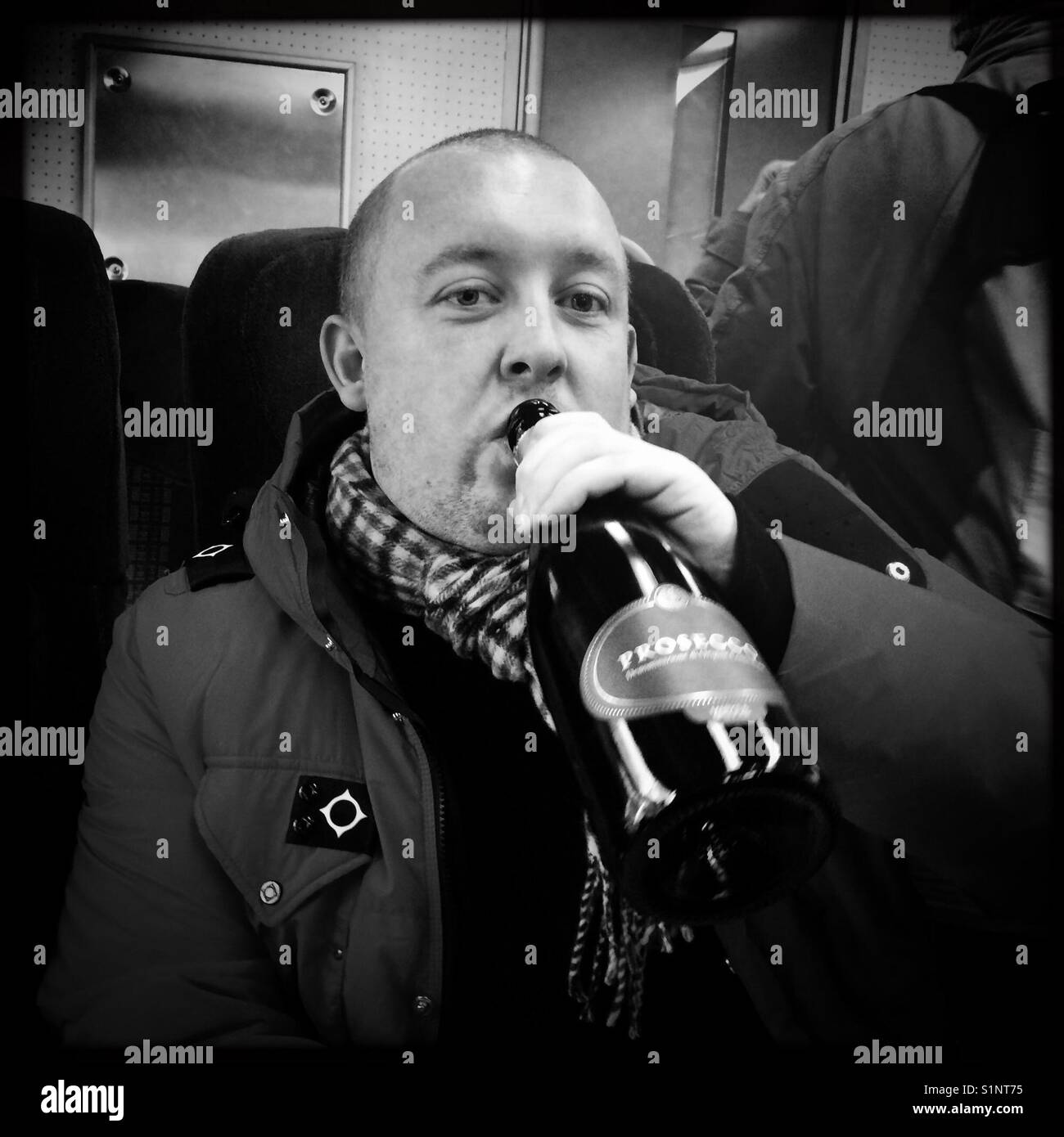 Man drinking bottle of Prosecco on train - Smartphone Captured Stock Image