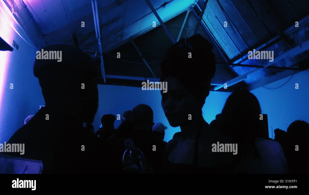 Silhouette of people against blue light inside a gallery during Peckham Rye Festival 2017 - Smartphone Captured Stock Image