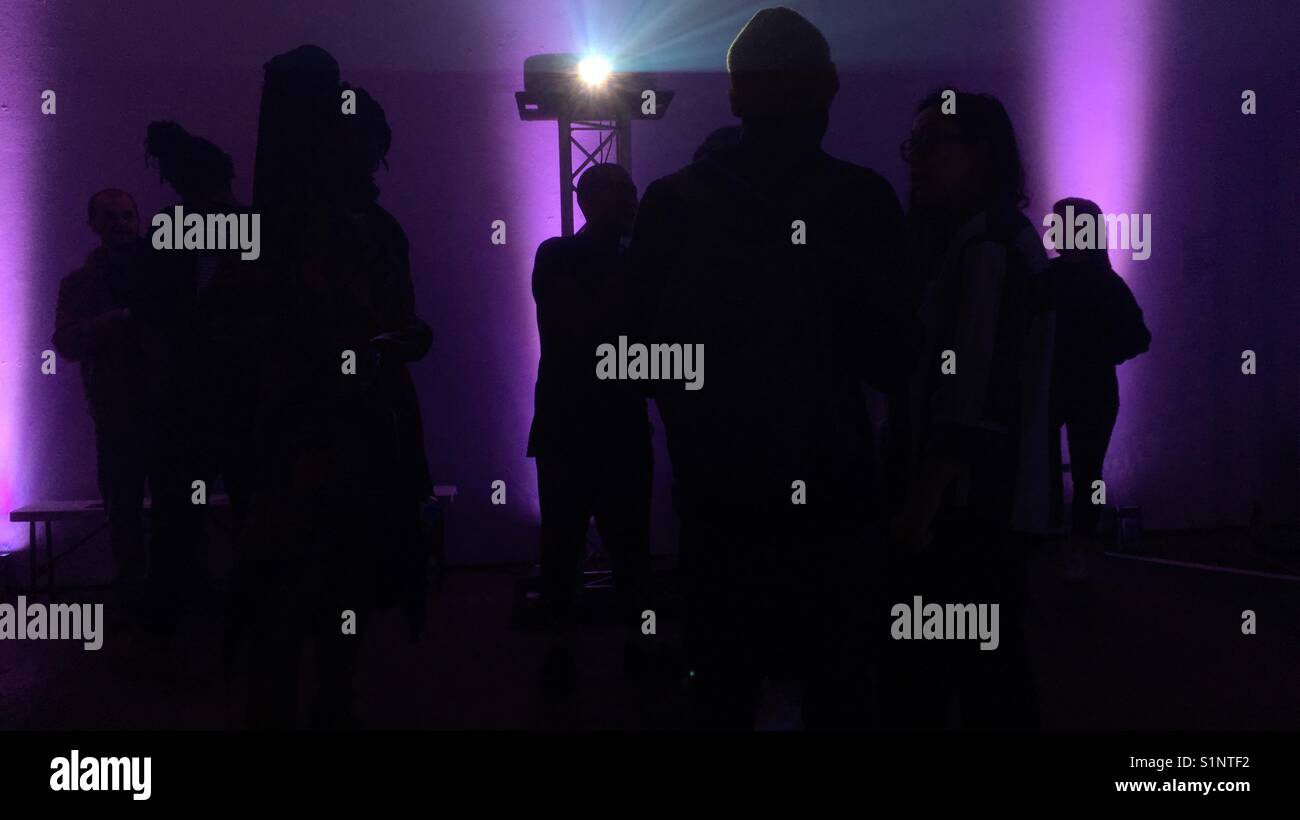 Silhouette of people against colourful light inside a music venue part of Peckham Rye festival in south east London. - Smartphone Captured Stock Image