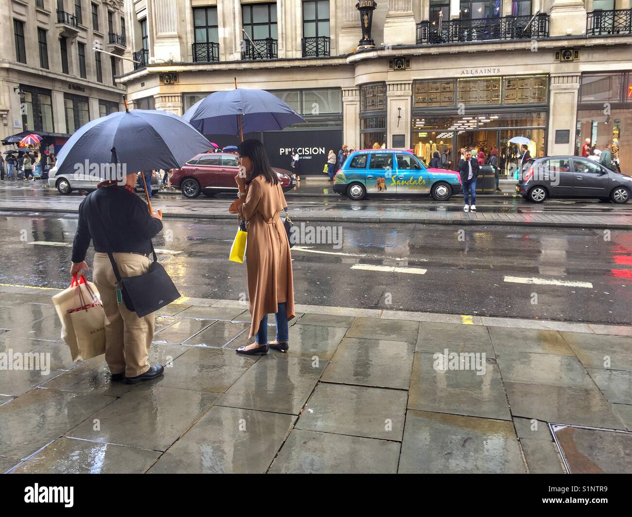 Shoppers stand under umbrella on Regents Street, London in England - Smartphone Captured Stock Image
