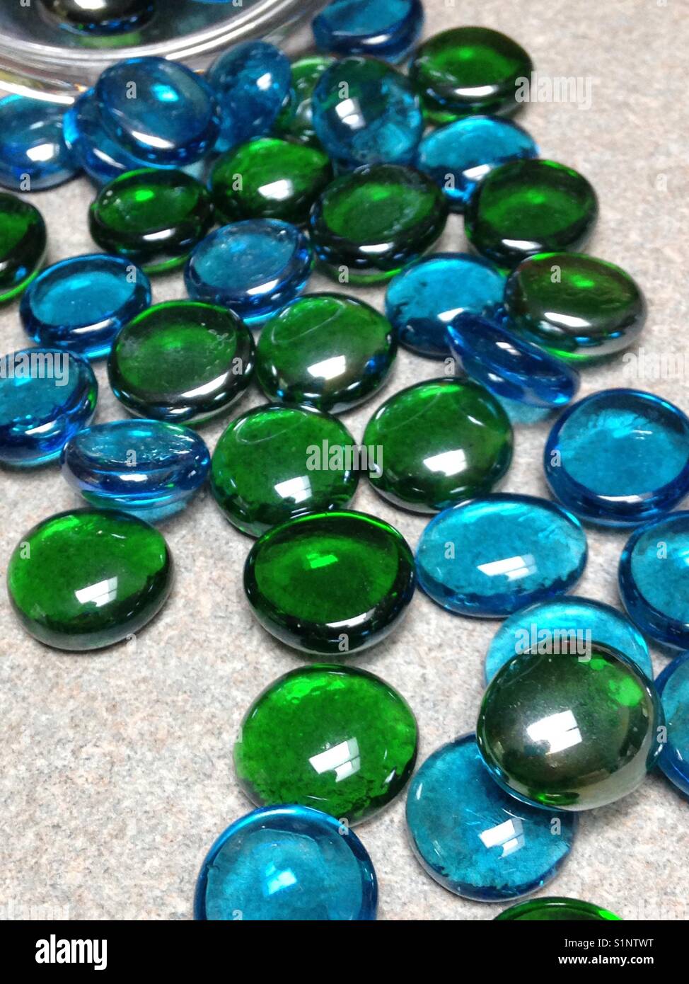Blue and green stones spilled out of a jar Stock Photo