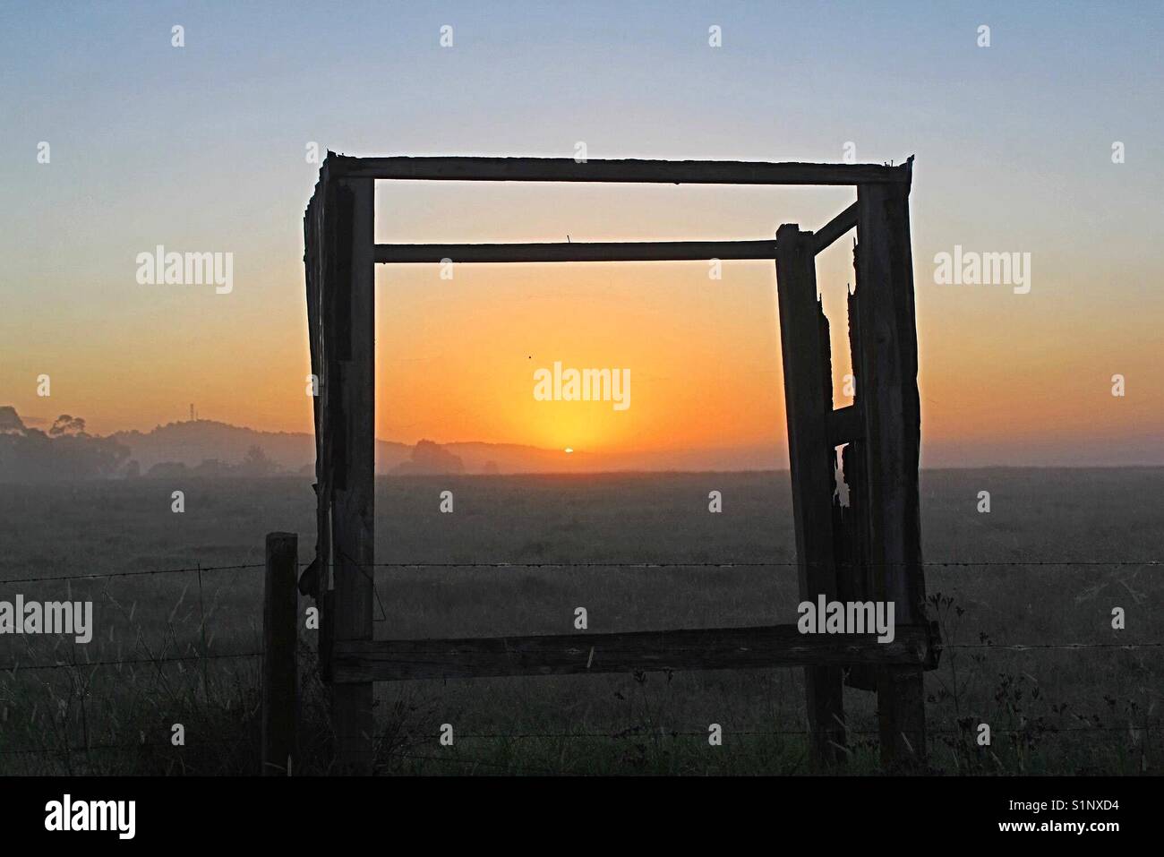 Sun rising framed through old shed - Smartphone Captured Stock Image