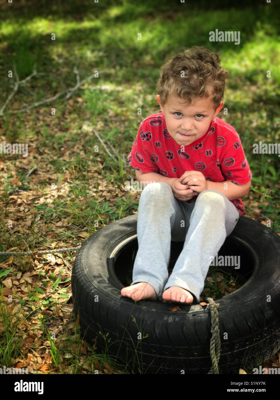 Boy sitting in an old tire Stock Photo Alamy