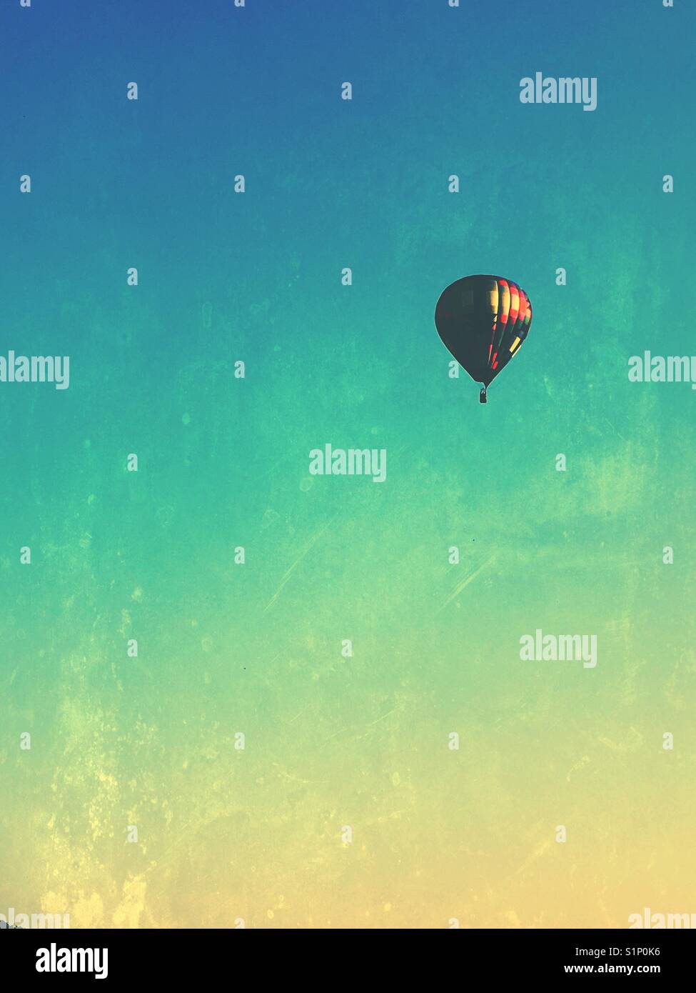 A multicolored hot air balloon floating in the sky.  A grunge filter added. - Smartphone Captured Stock Image
