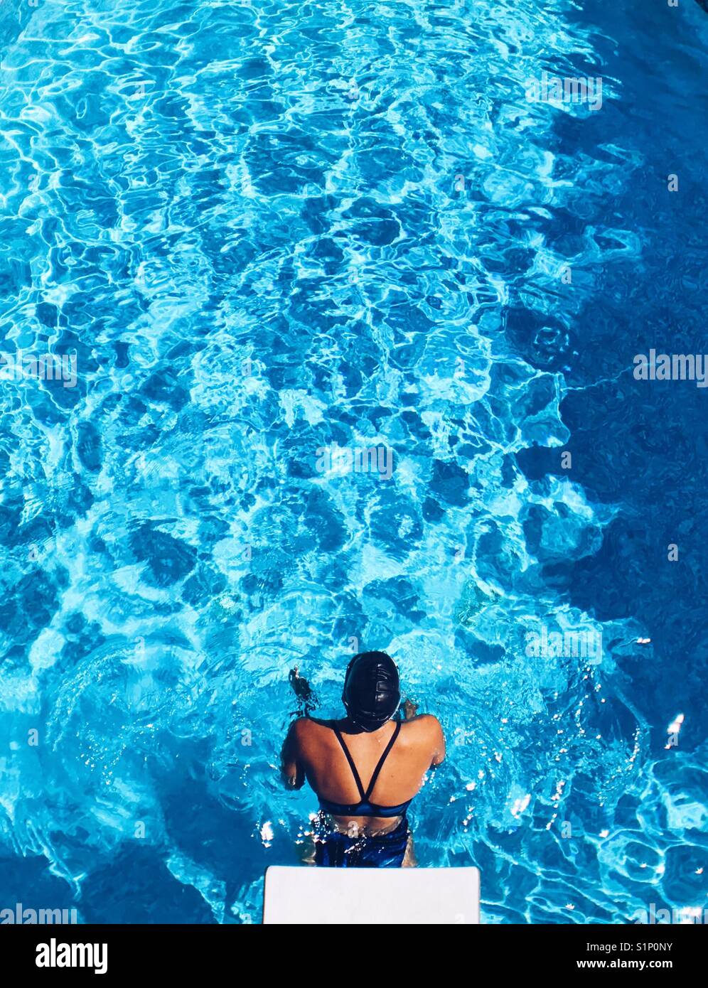Woman swimmer in a outdoor swimming pool on a sunny day. Bright edit. Stock Photo