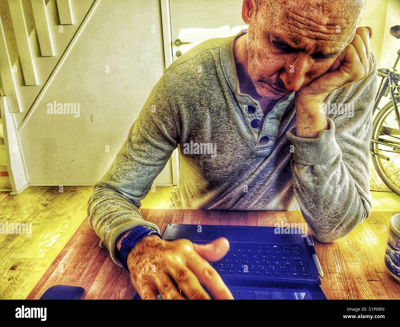 Tired serious middle aged Scandinavian man working on laptop at home Stock Photo