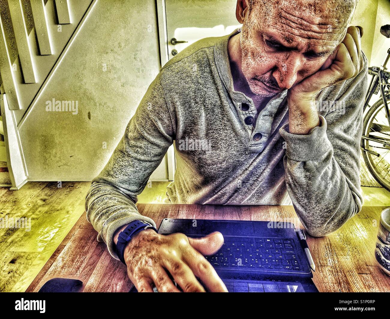 Serious bored middle aged Scandinavian man working on laptop at home Stock Photo