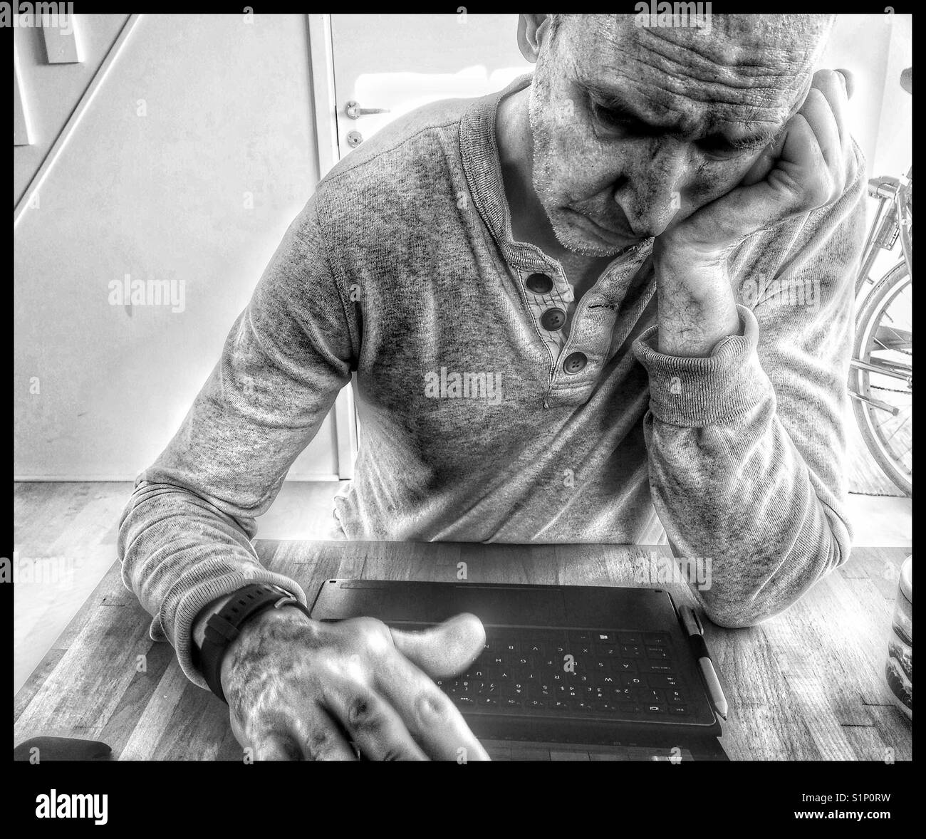 Sad and serious middle aged Scandinavian man working on laptop at home Stock Photo