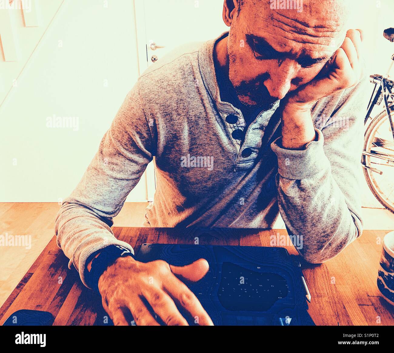 Sad and bored middle aged Scandinavian man working on laptop at home Stock Photo