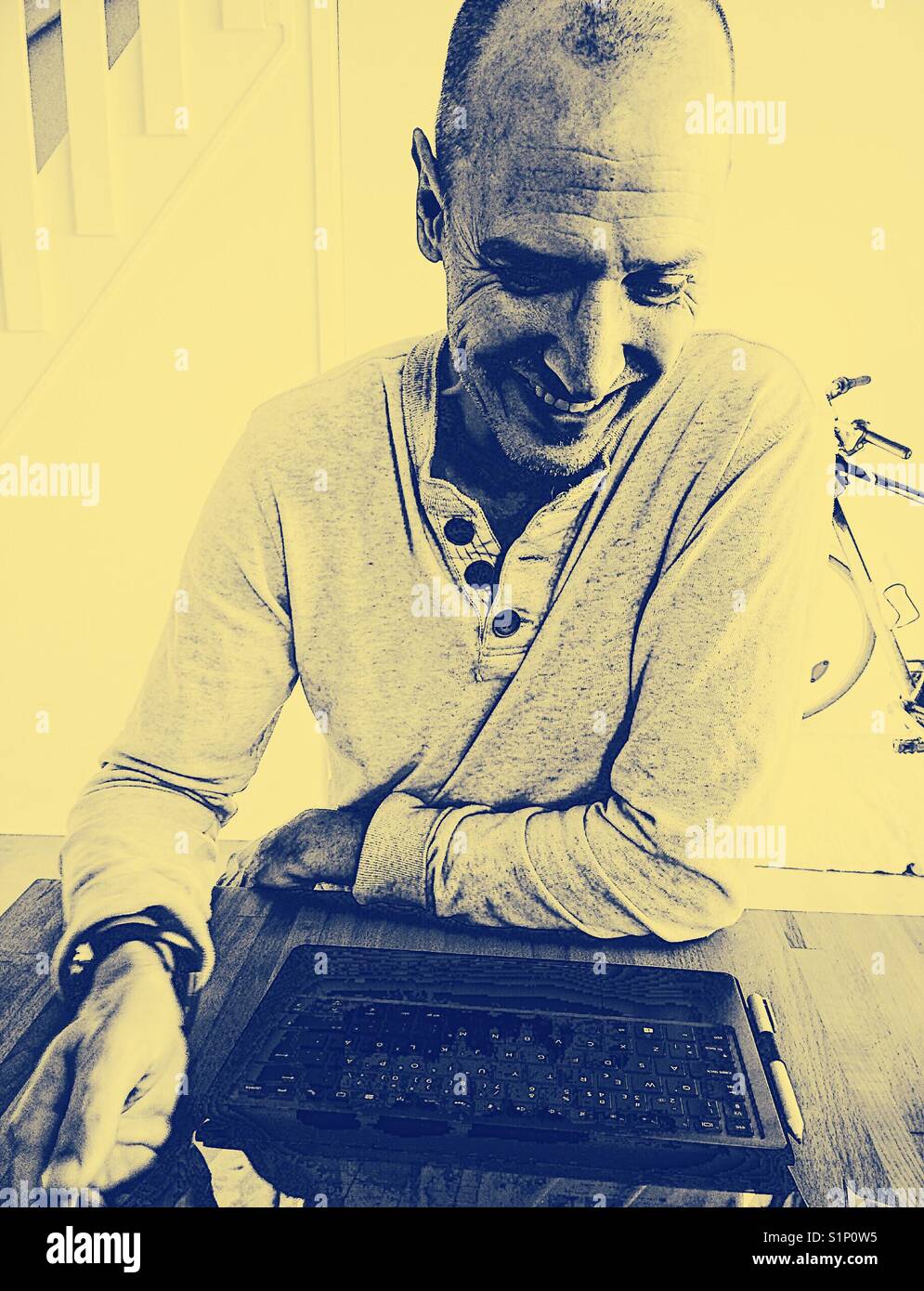 Smiling middle aged Scandinavian man working on laptop at home - Smartphone Captured Stock Image