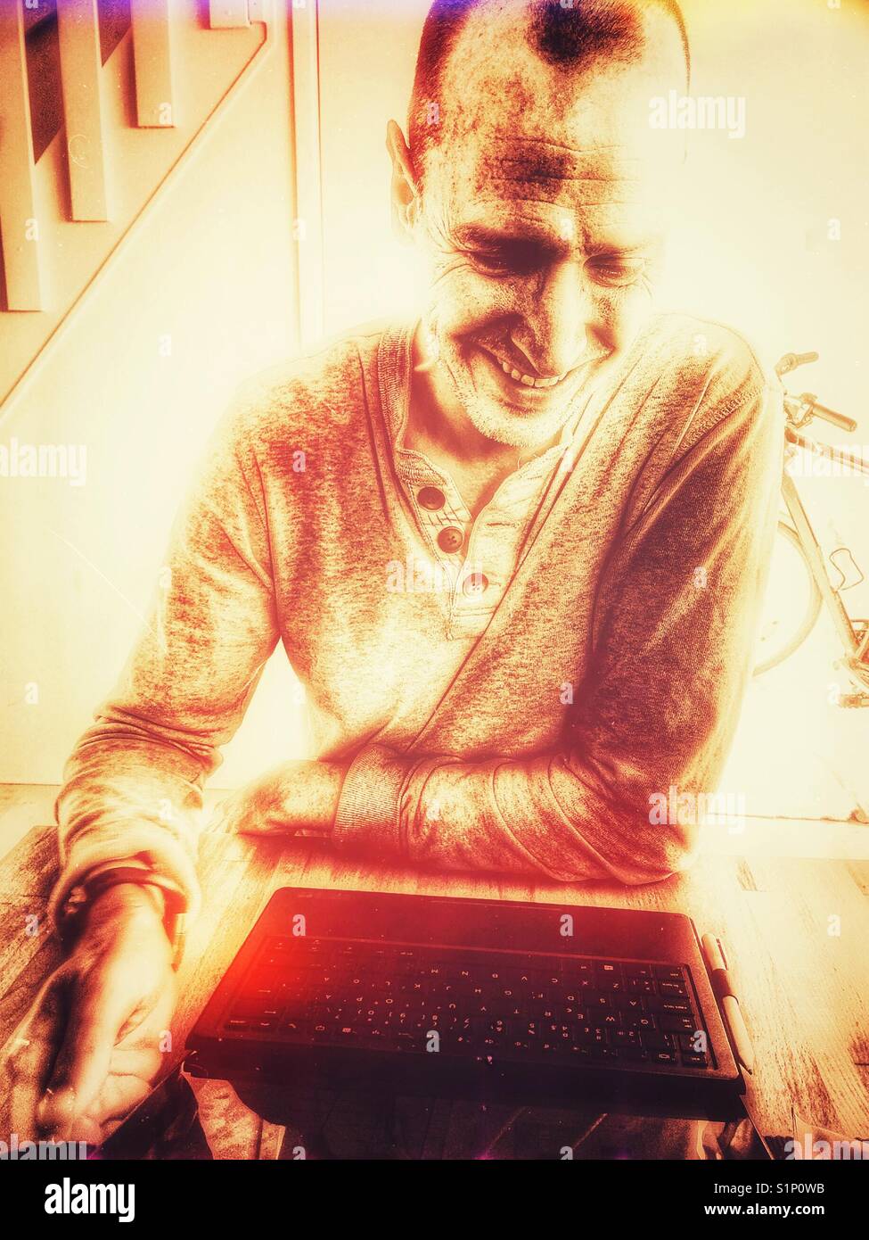 Smiling handsome middle aged Scandinavian man using laptop at home Stock Photo