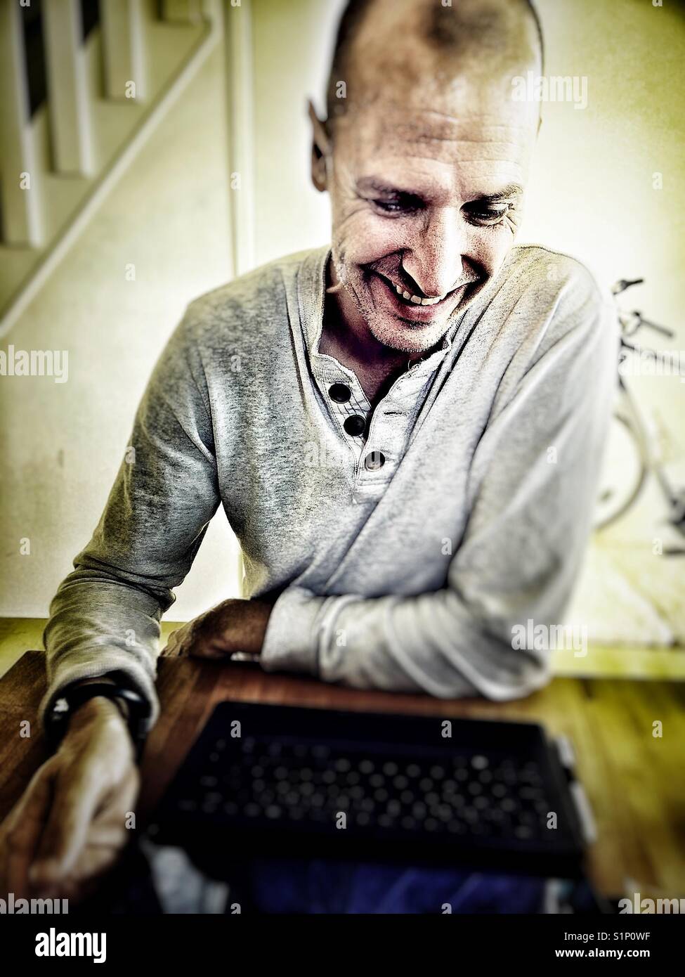 Happy middle aged Scandinavian man using laptop at home - Smartphone Captured Stock Image
