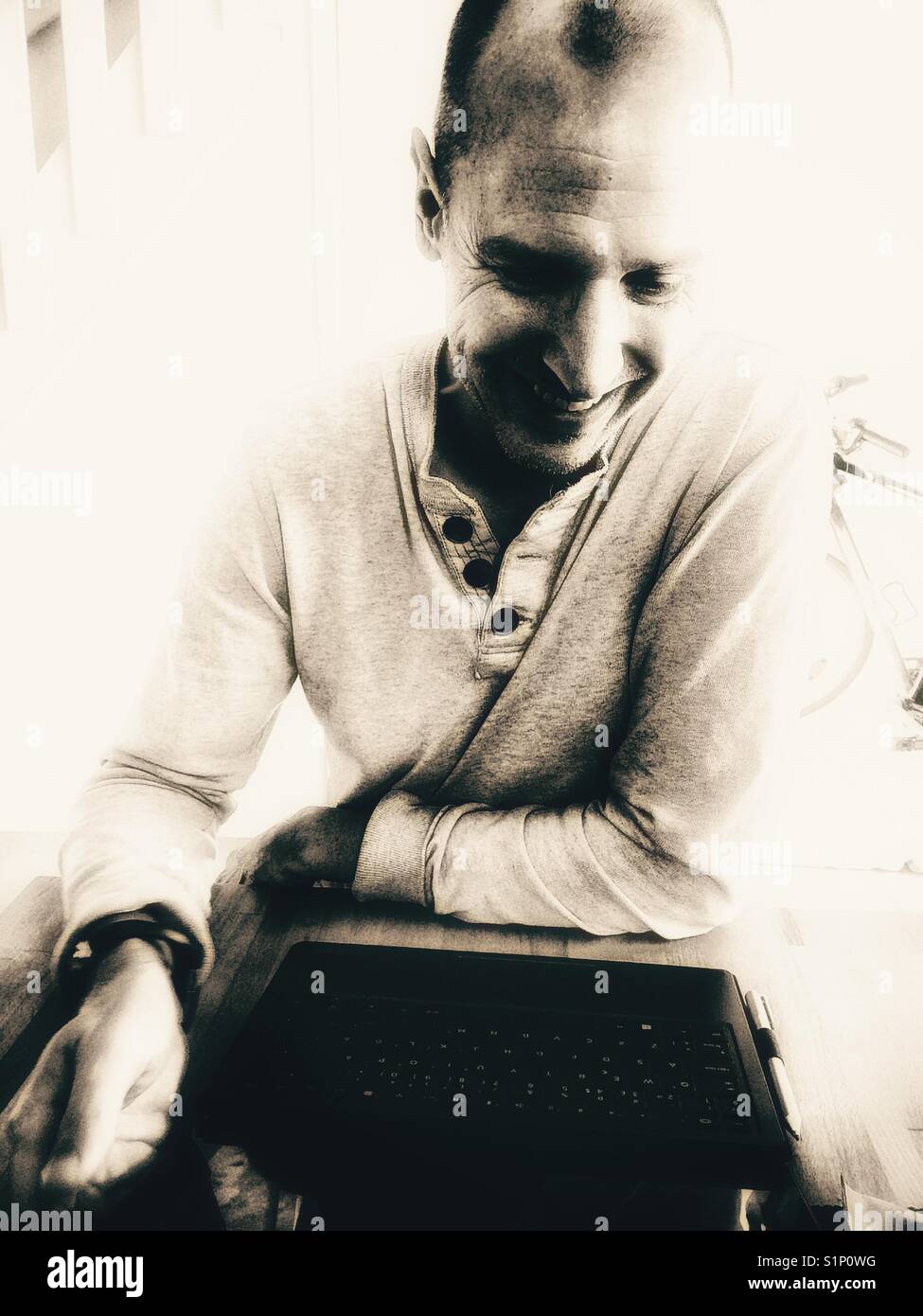 Happy smiling middle aged Scandinavian man working on laptop at home - Smartphone Captured Stock Image