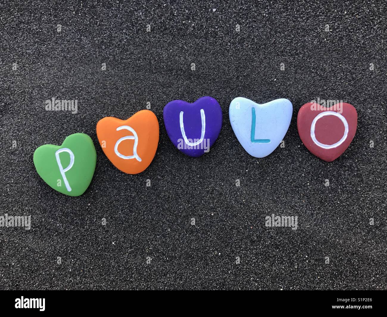 Paulo, masculine namewith colored heart stones over black volcanic sand Stock Photo