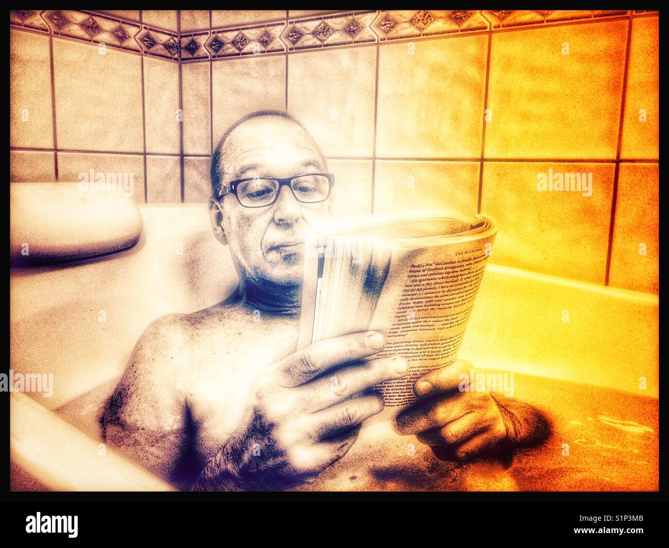 Middle aged man with glasses relaxing reading a book in the bath - Smartphone Captured Stock Image