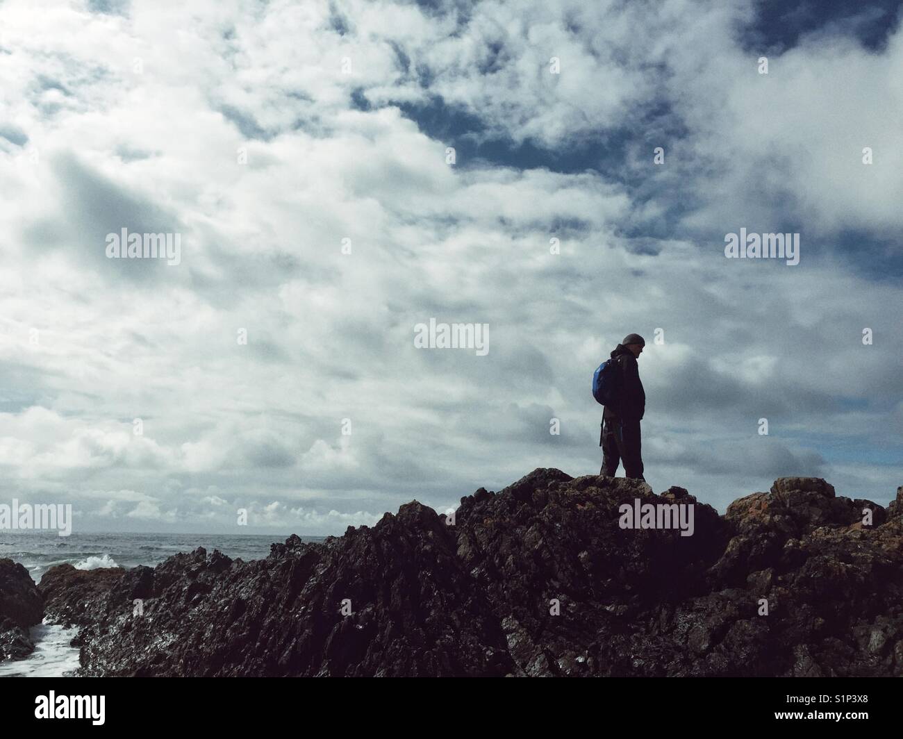 Man walking across rocks on Anglesey coast, north Wales - Smartphone Captured Stock Image