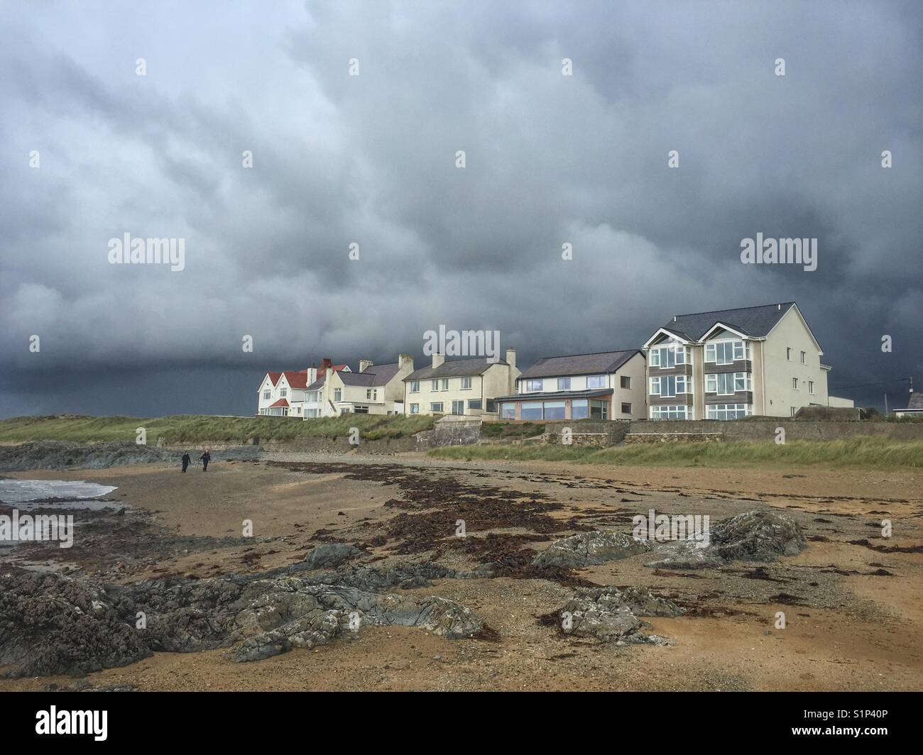 Walkers on Lion Rock beach, Rhosneigr, Anglesey, North Wales - Smartphone Captured Stock Image