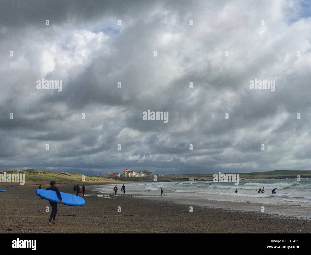 Surfer approaching the sea at Broad Beach, Rhosneigr, Anglesey, North Wales - Smartphone Captured Stock Image