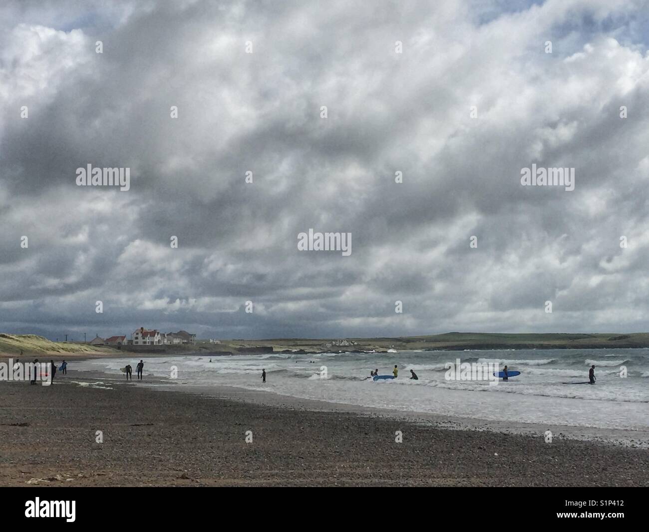 People surfing and kayaking at Broad Beach, Rhosneigr, Anglesey, north Wales - Smartphone Captured Stock Image