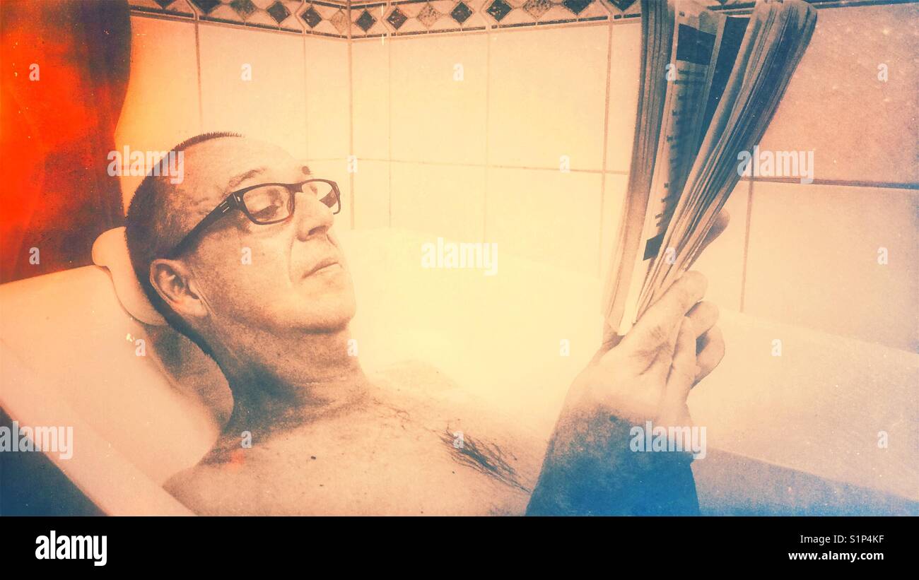 Middle aged man relaxing reading a book in the bath - Smartphone Captured Stock Image